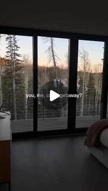 View through cabin windows toward a wooded mountain setting
